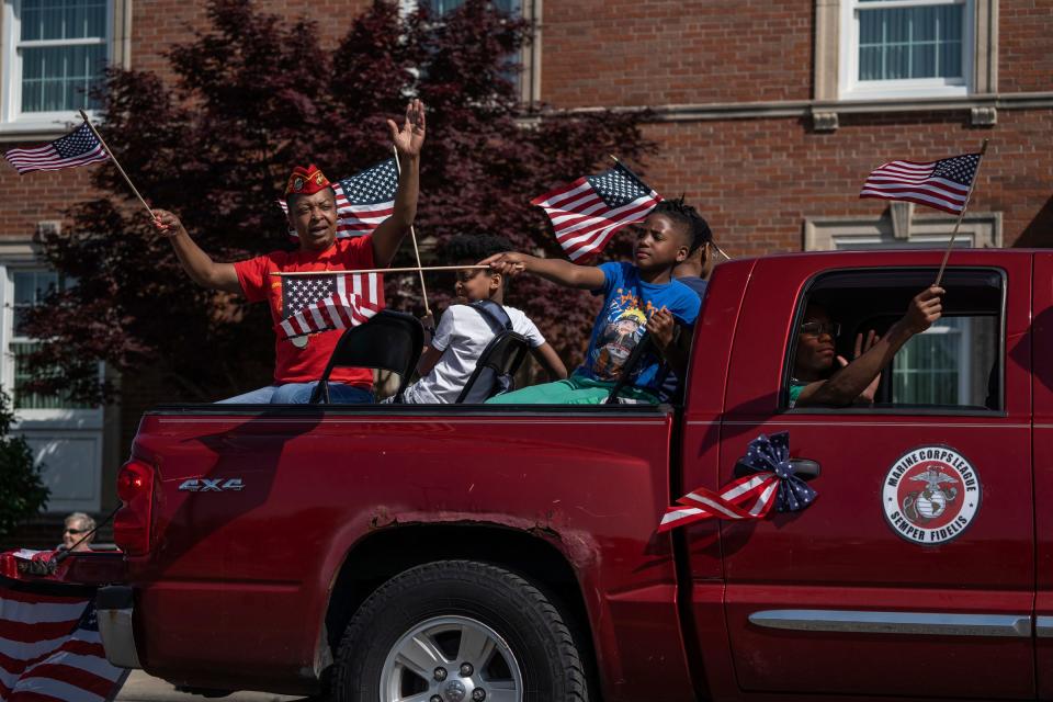 People wave while riding in a truck for the Marine Corps League while taking part in the 97th annual Memorial Day parade along Michigan Avenue in Dearborn on Monday, May 29, 2023.