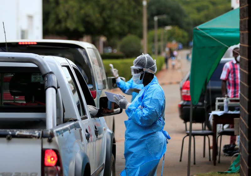 A health worker screens and sanitises visitors to prevent the spread of coronavirus disease (COVID-19) outside a hospital in Harare