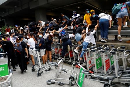 People and protesters run away from the riot police outside the terminals at Hong Kong International Airport