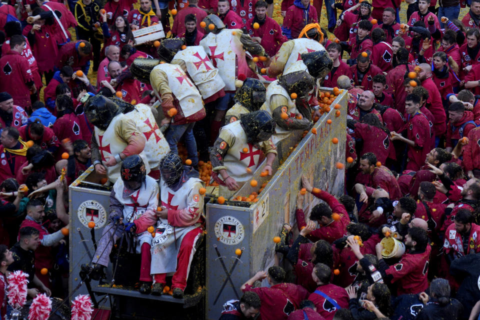 People wearing protection helmets and costumes pelt each other with oranges during the 'Battle of the Oranges" part of Carnival celebrations in the northern Italian Piedmont town of Ivrea, Italy, Tuesday, Feb. 13, 2024. (AP Photo/Antonio Calanni)