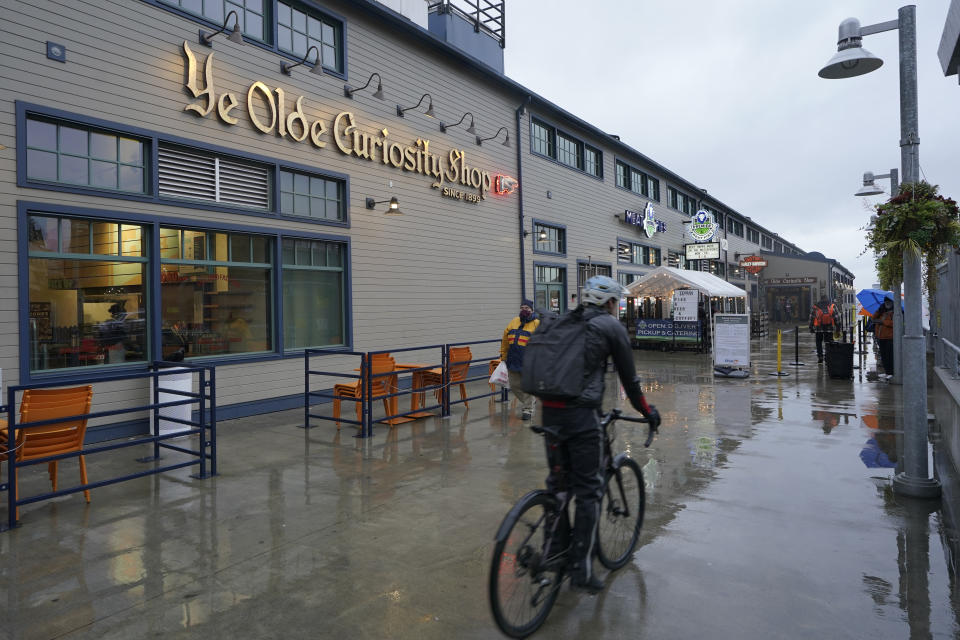 FILE - A cyclist rides past a sign for the Ye Olde Curiosity Shop on the Seattle waterfront, Dec. 10, 2021, in Seattle. Lewis Anthony Rath, of Maple Falls, Wash., who falsely claimed Native American heritage to sell his artwork at downtown Seattle galleries, was sentenced on Wednesday, Sept. 27, 2023, to probation and community service, the U.S. Attorney's Office said. (AP Photo/Ted S. Warren, File)