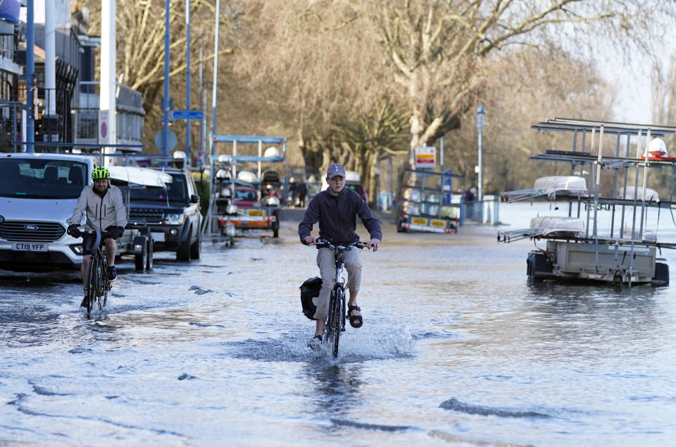 A cyclist travels through floodwater near the river Thames at Putney, London, Thursday Feb. 17, 2022, after Storm Dudley hit on Thursday night. Meteorologists warned Thursday that northern Europe could be battered by a series of storms over the coming days after strong winds swept across the region overnight. (Stefan Rousseau/PA via AP)