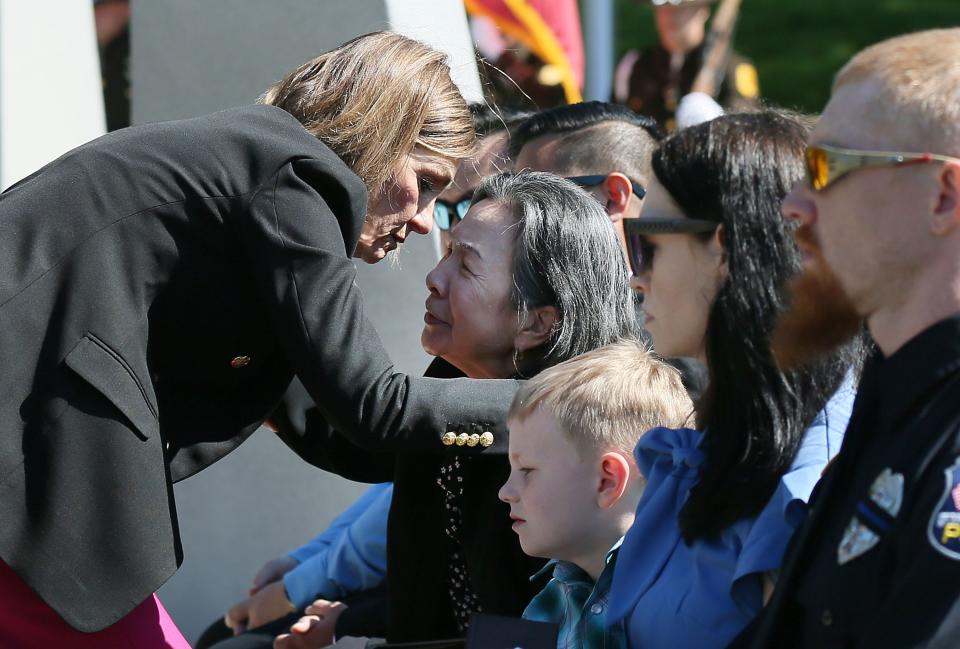 Iowa Gov. Kim Reynolds consoles the widow of Des Moines fallen officer Phoukham Tran, Chalouaiphone Tran, after giving her an American flag during a memorial ceremony at the Iowa Peace Officer Memorial on Friday, May 10, 2024, in Des Moines, Iowa.
