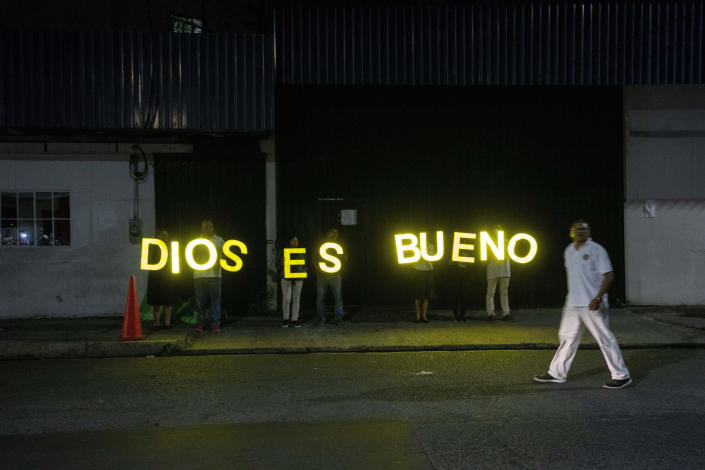 Christians hold letters that spell out in Spanish "God is good" as a pastor leads a prayer with relatives waiting for the release of their family members detained under the ongoing "state of exception", outside a detention center in San Salvador, El Salvador, Wednesday, Oct. 12, 2022. Civil and human rights groups say that arbitrary arrests are common and that when detainees finally see a judge they are almost automatically jailed for six months pending trial. Some people have died while incarcerated. (AP Photo/Moises Castillo)