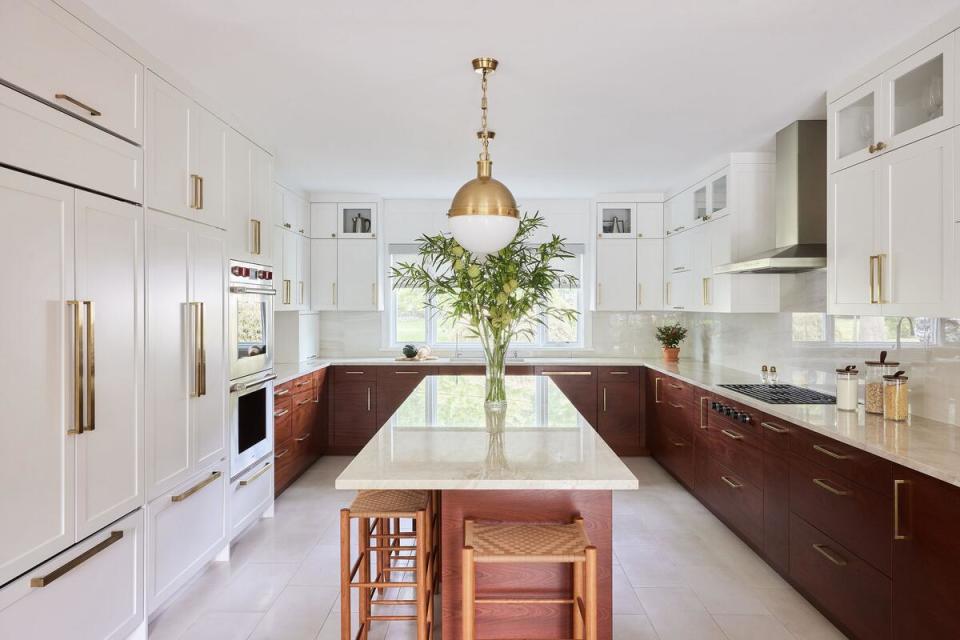 Warm wood on a kitchen’s lower cabinets creates a striking focal point amid the gleaming white wood and quartzite