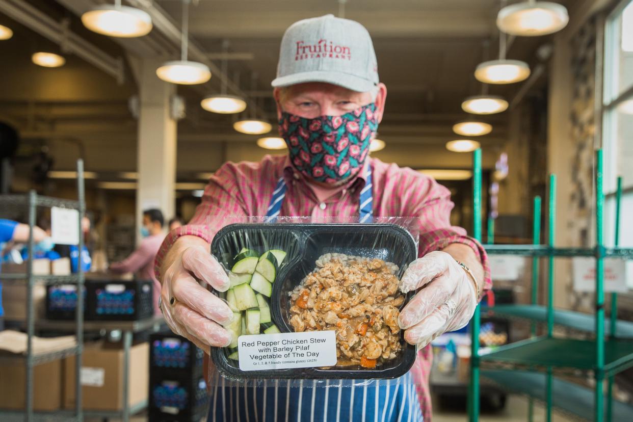 A Project Angel Heart volunteer shows off the contents of a medically tailored meal containing red pepper chicken stew with barley pilaf and vegetable of the day.