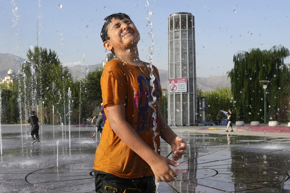 A young boy cools off in a water fountain at the Ebrahim Park while temperature reaches 38 C (100.4 F) in Tehran, Iran, Tuesday, Aug. 1, 2023. Iran announced a nationwide two-day, Wednesday and Thursday, holiday because of increasing temperatures. (AP Photo/Vahid Salemi)