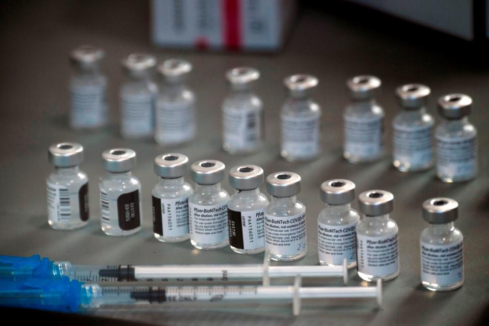 Vials of the Pfizer-BioNTech Covid-19 vaccine lined up on a table next to several syringes