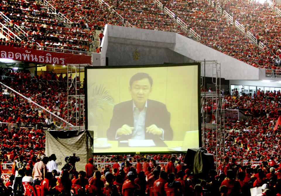 FILE - Pro-government and supporters of ousted Prime Minister Thaksin Shinawatra listen ousted Prime Minister Thaksin Shinawatra to speak from overseas exile to his supporters at Rajamangala national stadium in Bangkok, Thailand Saturday, Nov. 1, 2008. Thaksin Shinawatra, a controversial former Prime Minister of Thailand, made his dramatic return to Thailand last year after nearly a decade of self-imposed exile. Although he was detained in a hospital and never appeared in the public eye for six months after his arrival, his presence in the country alone brings a turmoil into Thai politics like no other politician could ever achieve. (AP Photo/Sakchai Lalit,File)