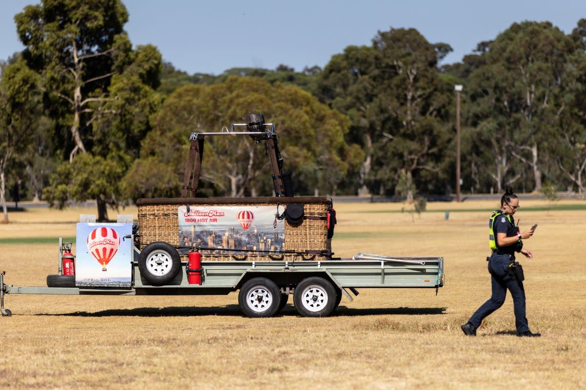 A police officer walks past a trailer with a hot-air balloon basket on it after the discovery of a man's body at Yarra Bend Park in Melbourne, Monday, 18 March 2024 (AP)