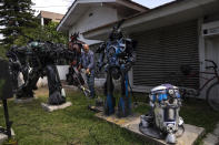 El jardinero Juan Acosta corta el césped de un patio delantero decorado con varios robots que se asemejan a los Transformers de la serie de televisión animada estadounidense de los años 80 y una réplica del personaje robot de Star Wars R2-D2 en Adrogué, Argentina, el viernes 28 de octubre de 2022. (AP Foto/Rodrigo Abd)