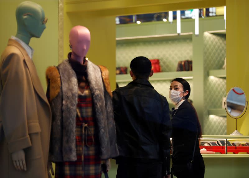 FILE PHOTO: A shop assistance wearing a protective face mask following an outbreak of the coronavirus talks to a customer at shopping mall in Tokyo