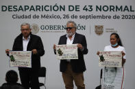 Mexico's President Andres Manuel Lopez Obrador, left, and Deputy Interior Secretary Alejandro Encinas, center, stand with Maria Martinez, mother of Miguel Angel Hernandez Martinez, as they hold cloths embroidered by mothers of some of 43 missing students from the Rural Normal School of Ayotzinapa, with a message reading in Spanish; "For the 43 and thousands of others, don't fail us, Ayotzinapa," following a presentation on the ongoing investigation on the sixth anniversary of the students enforced disappearance, at the National Palace in Mexico City, Saturday, Sept. 26, 2020.(AP Photo/Rebecca Blackwell)