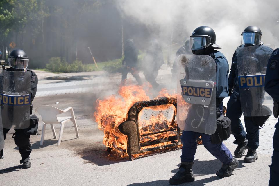 <p>Police walk past furniture set on fire by protesters during a demonstration in Quebec City on June 8, 2018, as the G7 Summits gets underway. (Photo: Alice Chiche/AFP/Getty Images) </p>