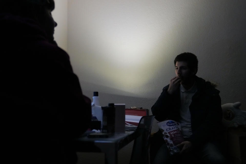 Jarod Valentin, right, eats dried cranberries inside his apartment after an earthquake in Rio Dell, Calif., Tuesday, Dec. 20, 2022. A strong earthquake shook a rural stretch of Northern California early Tuesday, jolting residents awake, cutting off power to 70,000 people, and damaging some buildings and a roadway, officials said. Two injuries were reported. (AP Photo/Godofredo A. Vásquez)