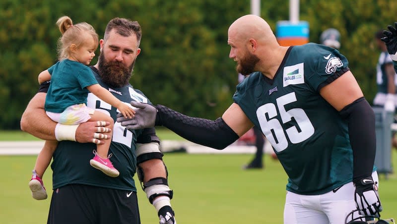 Philadelphia Eagles center Jason Kelce, left, shows off his daughter to offensive tackle Lane Johnson, right, during practice at NFL football training camp, Thursday, July 29, 2021, in Philadelphia.