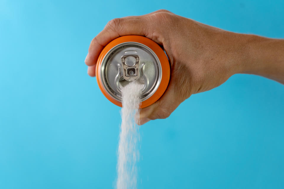 Hand holding soda can pouring lots of sugar in metaphor of sugar content of a refresh drink in healthy nutrition, diet, sweet and carbonated drinks addiction and unhealthy food concept.