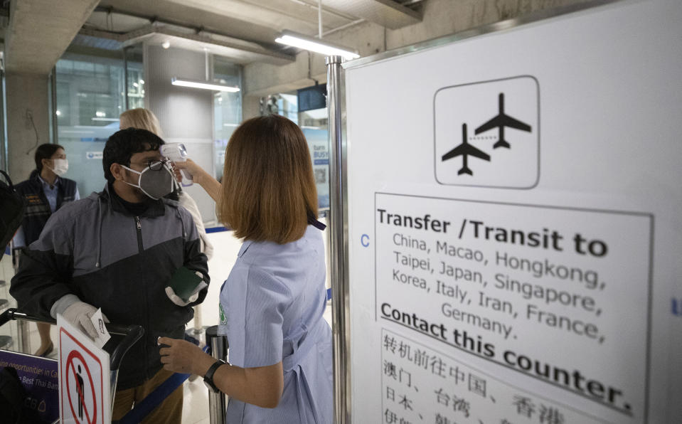 Health officials check tourists' temperatures in hopes of containing the spread of the COVID-19 virus as they arrive at Suvarnabhumi Airport Bangkok, Thailand, Wednesday, March 4, 2020. (AP Photo/Sakchai Lalit)
