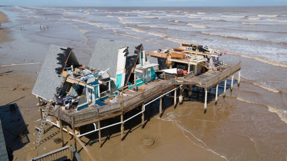 aerial view shows the damage by hurricane Beryl. Most of the roof is missing with the interior of the home exposed, some of it is completely flattened. It is located on a beach.