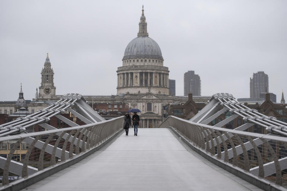 People walk across the Millennium Bridge in London, Monday Dec. 21, 2020. Millions of people in England have learned they must cancel their Christmas get-togethers and holiday shopping trips. British Prime Minister Boris Johnson said Saturday that holiday gatherings can’t go ahead and non-essential shops must close in London and much of southern England. (Dominic Lipinski/PA via AP)