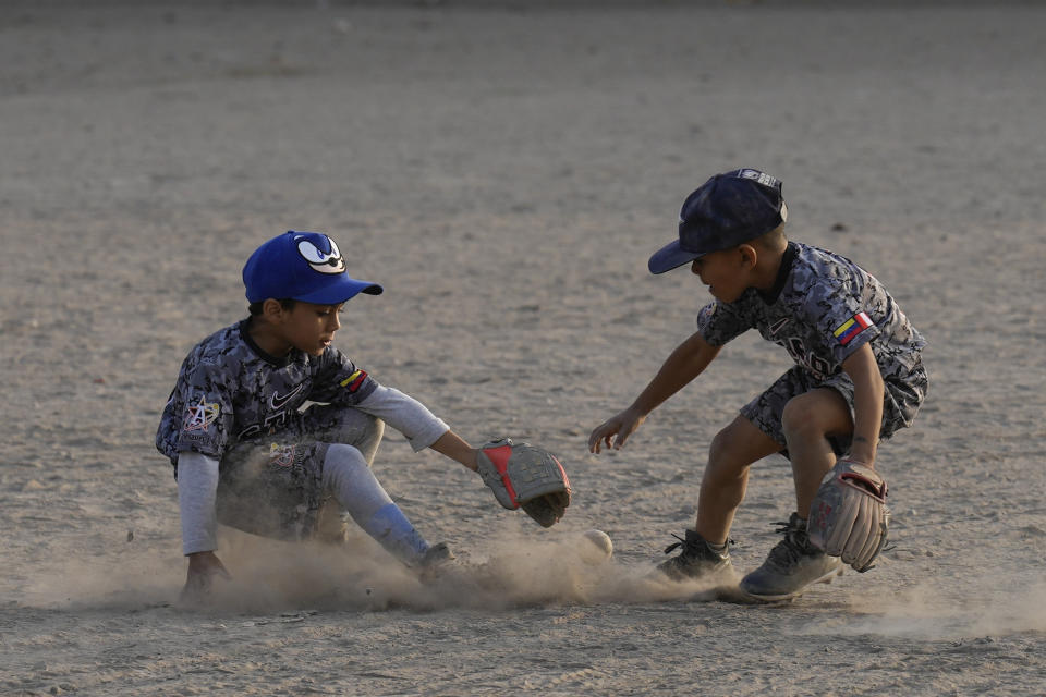 Young Venezuelan migrants vie for the ball in a practice baseball session at a public park in the Comas area, on the outskirts of Lima, Peru, Thursday, May 9, 2024. Immigrants, mainly Venezuelans, have opened five baseball academies in Peru's capital. (AP Photo/Martin Mejia)