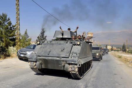 Lebanese army soldiers flash victory signs while riding on armoured carriers and military vehicles as they advance towards the Sunni Muslim border town of Arsal, in eastern Bekaa Valley as part of reinforcements August 6, 2014. REUTERS/Hassan Abdallah