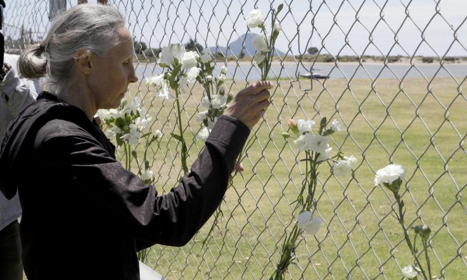 A woman places flowers at a fence on the waterfront in Whakatāne.