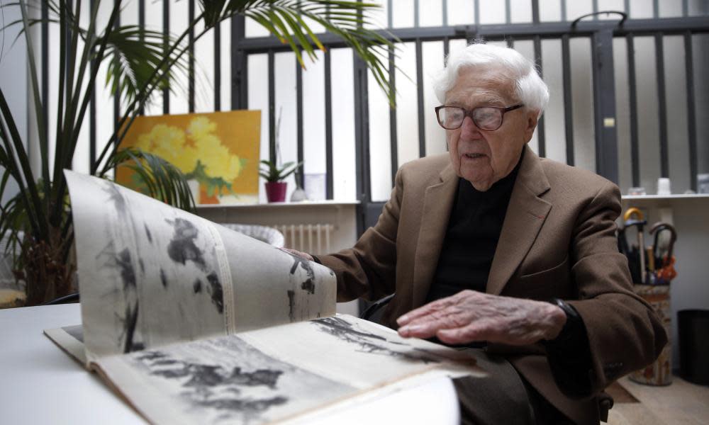 John Morris looking at Robert Capa pictures from D-day during an interview in Paris in 2014.