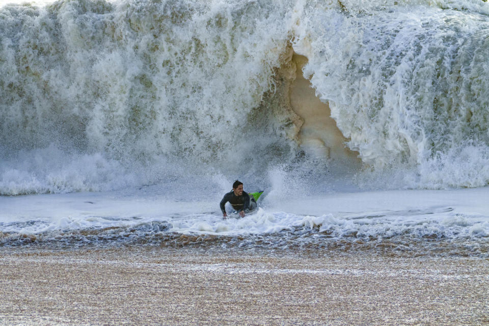 A surfer emerges under the waves in Seal Beach, Calif., Saturday, Dec. 30, 2023. (AP Photo/Damian Dovarganes)