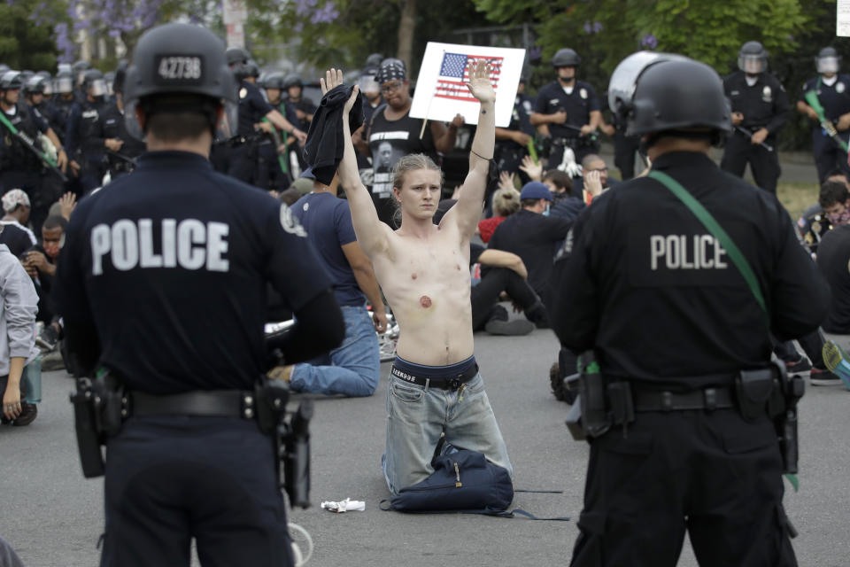 FILE - In this June 1, 2020, file photo, a protester, who appears to have a bruise from a rubber bullet, raises his arm shortly before being arrested for violating a curfew n the Hollywood area of Los Angeles. The Los Angeles Police Department is investigating 56 allegations of misconduct during protests against police brutality in the wake of George Floyd's death. Of the 56 investigations, 28 involve alleged uses of force, the LAPD said Wednesday, June 10, 2020 in a statement. Seven officers have been taken out of the field. While most protests have been peaceful, there were violent clashes with police and businesses were vandalized. (AP Photo/Marcio Jose Sanchez, File)