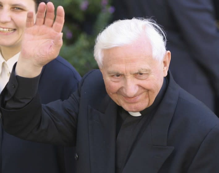 FILE - In this Monday, Aug. 15, 2005 filer, the Reverend Georg Ratzinger, brother of Pope Benedict XVI, waves as he walks in Castel Gandolfo, near Rome, where the pontiff greeted the faithful for Assumption day celebrations. The Rev. Georg Ratzinger, the older brother of Emeritus Pope Benedict XVI, who earned renown in his own right as a director of an acclaimed German boys' choir, has died at age 96. The Regensburg diocese in Bavaria, where Ratzinger lived, said in a statement on his website that he died on Wednesday, July 1, 2020. (AP Photo/Alessandra Tarantino, File)