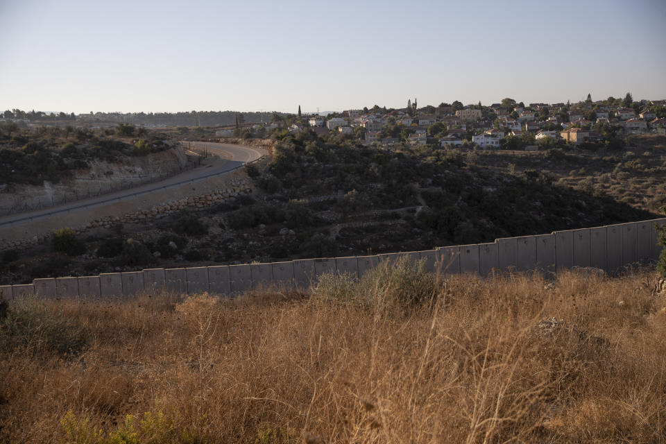 The Israeli settlement of Hashmona'im is seen behind a section of Israel's separation barrier in the West Bank village of Nilin, west of Ramallah, Sunday, Nov. 7, 2021. Nearly two decades after Israel sparked controversy worldwide by building the barrier during a Palestinian uprising, it has become a seemingly permanent feature of the landscape — even as Israel encourages its citizens to settle on both sides. (AP Photo/Nasser Nasser)