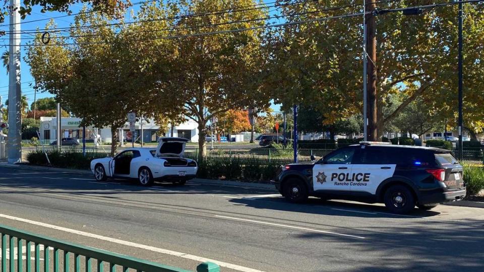 A Dodge Challenger and a Rancho Cordova police vehicle are seen on Folsom Boulevard near Mather Field Road following an officer-involved shooting Monday, Nov. 20, 2023. The Sacramento County Sheriff’s Office, which contracts police services for the city, said two deputies fired on a woman.