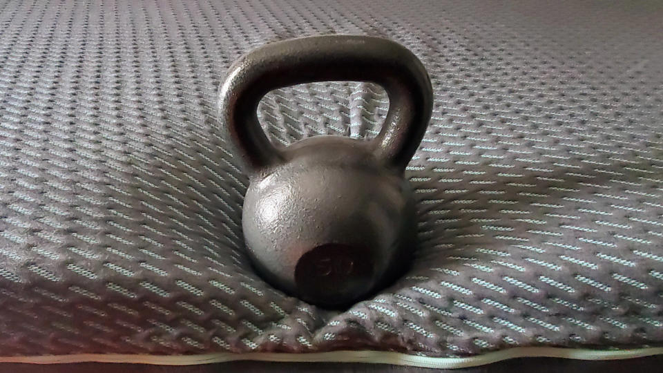 A kettlebell on the edge of the Tuft & Needle Mint Hybrid mattress