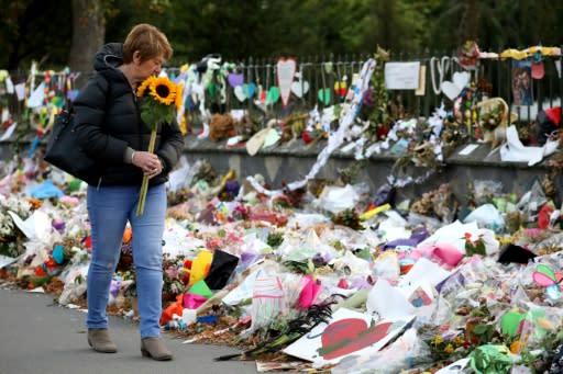 A woman walks past flowers and tributes displayed in memory of the twin mosque massacre victims at the Botanical Garden in Christchurch