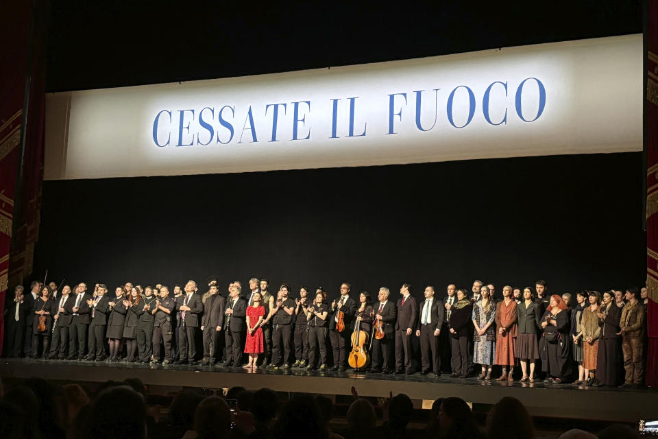 La Scala's dance company and the orchestra stand on stage before the final performance of the opera-ballet "Madina" beneath a banner reading: "Ceasefire" in Milan, Italy, Saturday, March 9, 2024. The sentiment received a standing ovation lasting at least two minutes Saturday evening before the final performance of the opera house's original production “Madina,” which tells the story of a Chechen woman who is manipulated to become a suicide bomber after she is orphaned and raped by Russian soldiers. (AP Photo/Colleen Barry)
