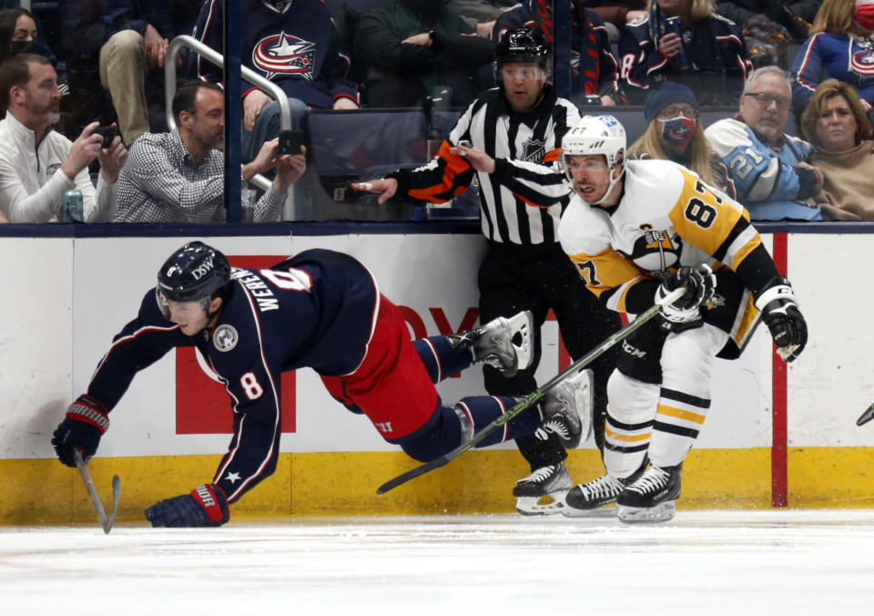 Pittsburgh Penguins forward Sidney Crosby, right, trips Columbus Blue Jackets defenseman Zach Werenski during the second period of an NHL hockey game in Columbus, Ohio, Friday, Jan. 21, 2022. Crosby was called for a penalty on the play. (AP Photo/Paul Vernon)