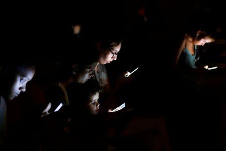 People surf the internet on their mobile devices at a hotspot in Havana, Cuba, July 10, 2018. REUTERS/Stringer