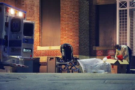 A man collects and bags items behind the ambulance used to transport a patient with possible Ebola symptoms to Beth Israel Deaconess Medical Center in Boston, Massachusetts October 12, 2014. REUTERS/Brian Snyder