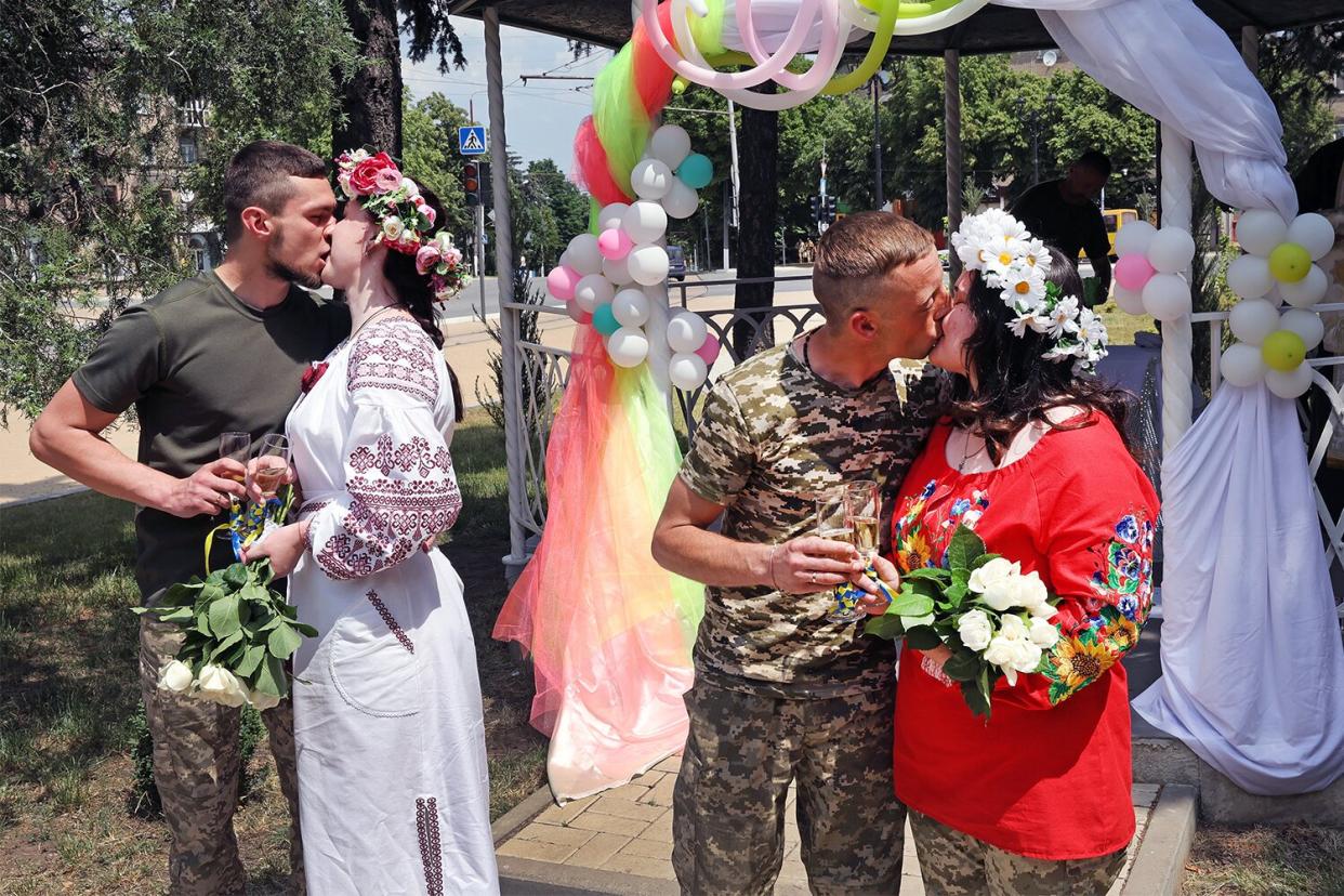 Soldiers Vitalii Orlich and his bride Kristina (L) and Volodymyr Mykhailuk and his bride Hrystyna kiss after being married during joint wedding ceremony on June 12, 2022 in Druzhkivka, Donetsk Oblast, Ukraine. All four are soldiers in the Ukrainian army serving with the 14th separate mechanized brigade in eastern Ukraine. Both couples met while serving in the army after the start of the war with Russia. Ukrainian forces are engaged in a back-and-forth battle with Russia for key towns along the western edge of the Donetsk and Luhansk regions, where Moscow is focusing its firepower.