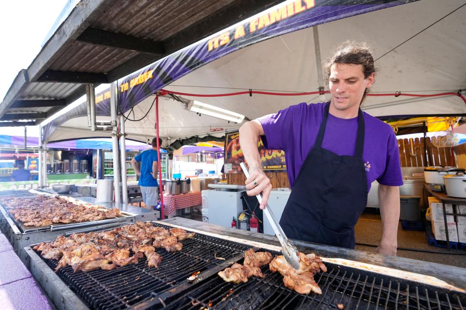 Troy Fletcher, of Mount Orab, Brown County, flips pieces of bourbon chicken on the grill at the Ohio State Fair.