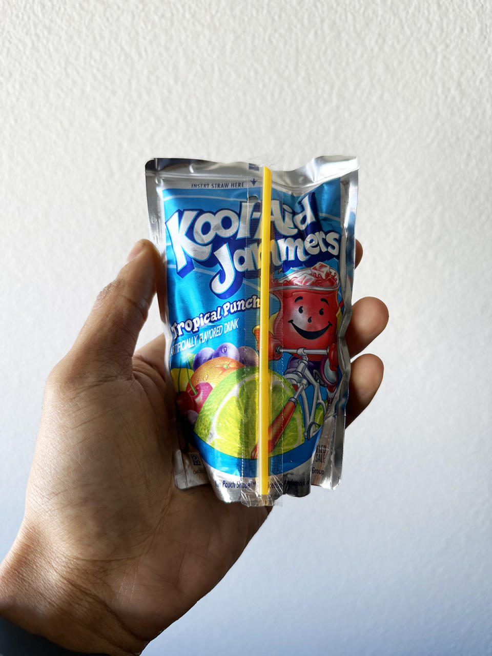 A hand holding a Kool-Aid Jammers Tropical Punch pack