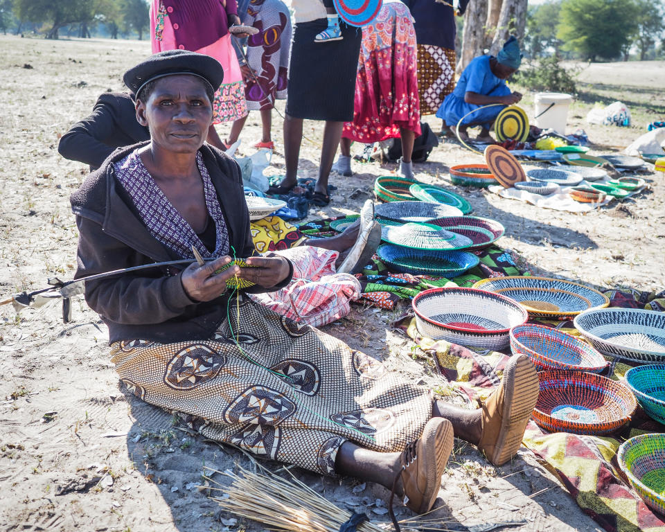 African woman weaving traditional baskets out of modern materials