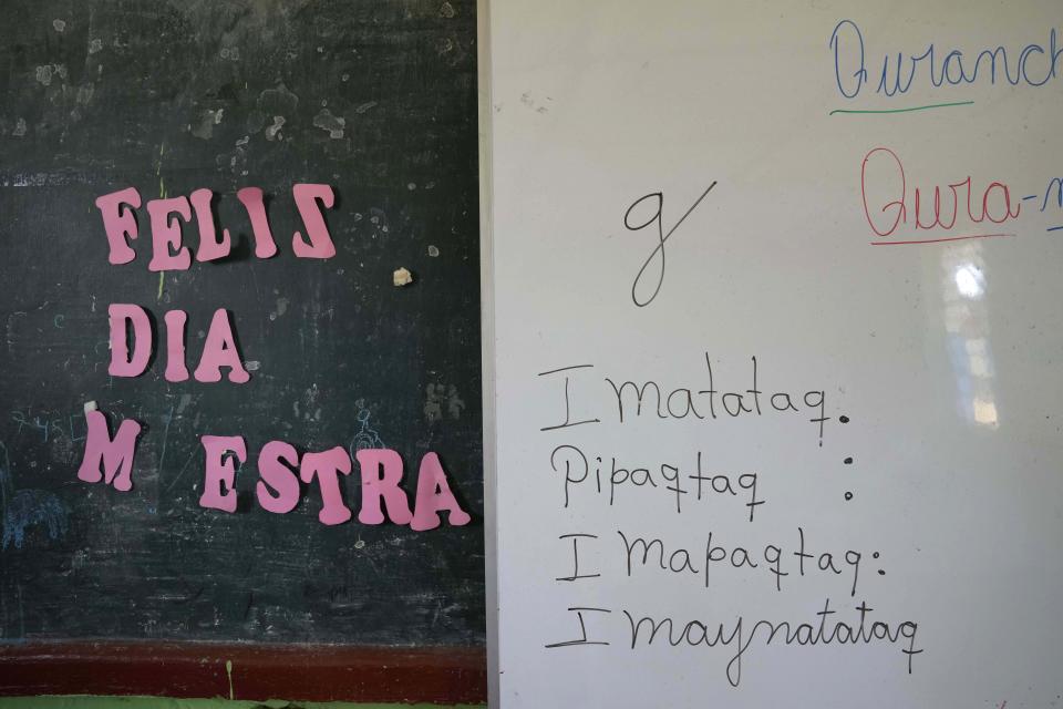 The Spanish phrase "Happy Day Teacher," left, hangs next to a white board of words in the Indigenous Quechua language, during language class at a public primary school in Licapa, Peru, Wednesday, Sept. 1, 2021. More than 1.2 million children receive bilingual education in Spanish and Indigenous languages across Peru, a nation of about 32 million people. (AP Photo/Martin Mejia)