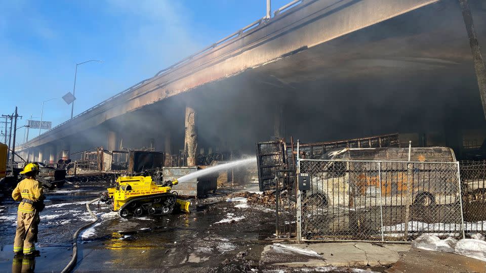 A Los Angeles firefighter uses a robotic hose to douse a fire under Interstate 10 that severely damaged an overpass in downtown Los Angeles on Saturday. - Caltrans District 7/AP