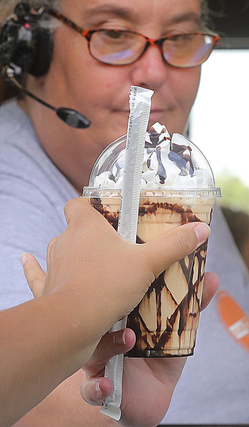 Double Shot Coffee Drive Thru worker Margie Ivens hands a choco nut breve to a customer.