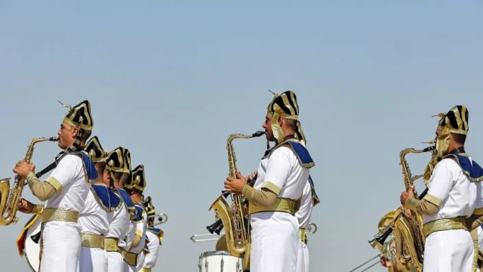 A group of men playing the saxophone wearing ancient Egyptian clothes.