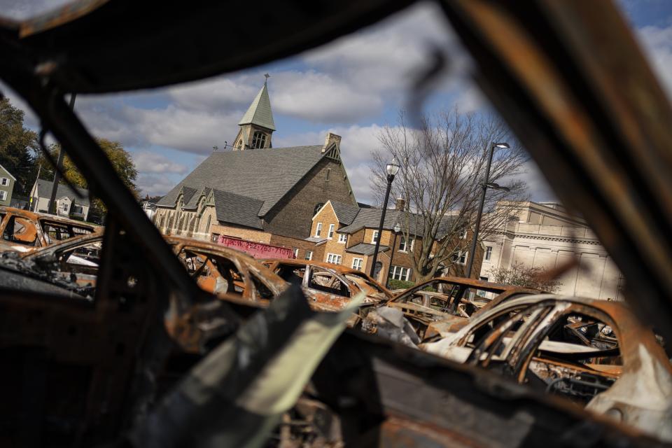 A church building is framed by the remains of burnt vehicles in Kenosha, Wis., Friday, Oct. 30, 2020. The trouble in Kenosha began on Aug. 23 when a Kenosha police officer, responding to a call about a domestic dispute, was caught on video shooting Jacob Blake repeatedly in the back at close range. Blake, a Black man, survived but is partially paralyzed. The August shootings have spurred a spike in political involvement in Kenosha, with the formation of activism and waves of new voters signing up. (AP Photo/Wong Maye-E)