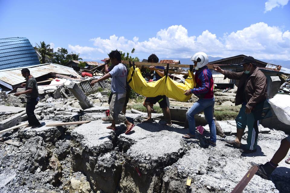 In this Sunday, Sept. 30, 20128, file photo, villagers carry the body of a victim following earthquakes and tsunami in Palu, Central Sulawesi, Indonesia. (AP Photo/Arimacs Wilander, File)