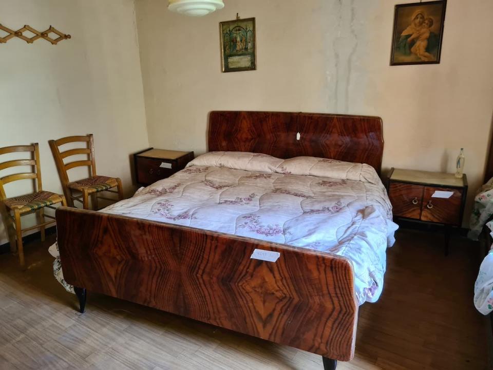 A wooden bed, chairs, bedside tables, and paintings.